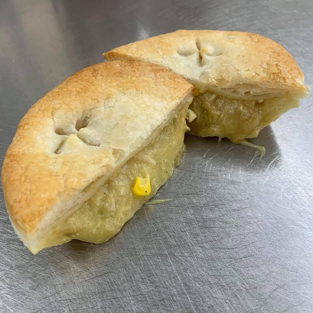 A chicken pie cut in half on the bakery bench, showing creamy filling